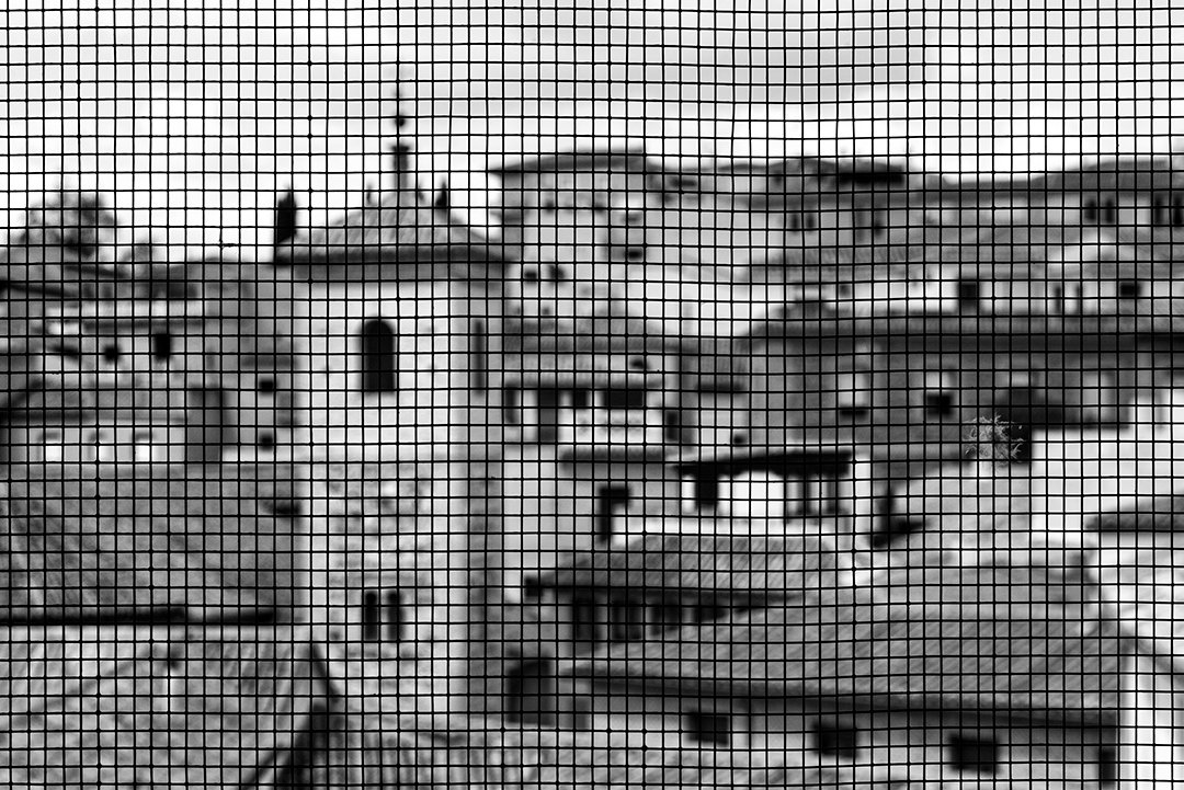 Buildings seen through a mesh screen.
